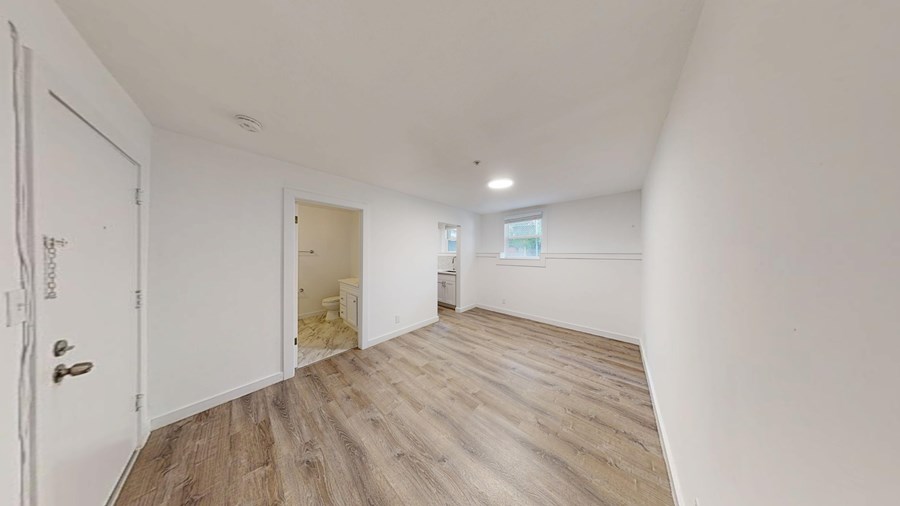 A room with a white door and wooden flooring.